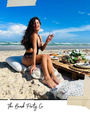 Woman enjoying a beach picnic with wine and sunshine.