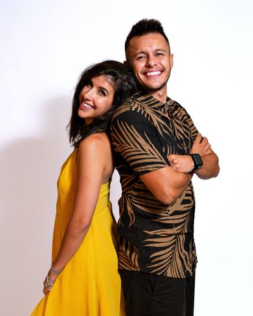 Smiling couple standing back to back against a white background.