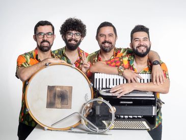 A cheerful band of four men posing with musical instruments against a white background.