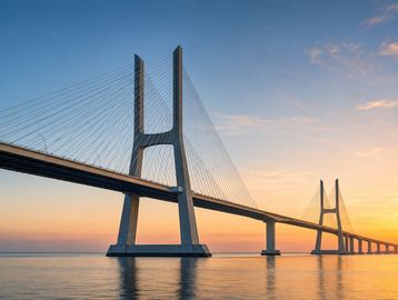 A cable-stayed bridge over calm water during sunset.