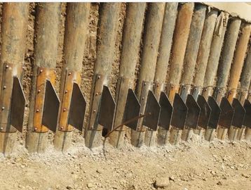 Metal brackets attached to vertical wooden posts on a dirt ground.