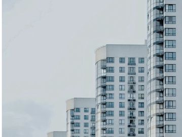 Row of modern white apartment buildings with balconies against a gray sky.