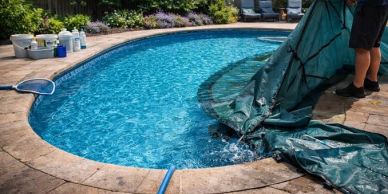 Person cleaning a backyard pool with a tarp.