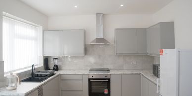 Modern kitchen with gray cabinets and white countertops.
