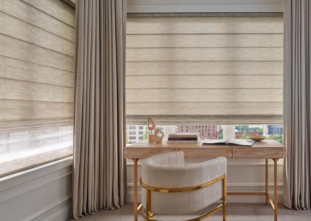 Elegant home office with beige curtains, Roman shades, and a stylish desk and chair.
