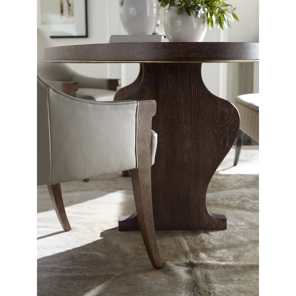 Close-up of a wooden dining table with leather chairs on a textured rug.