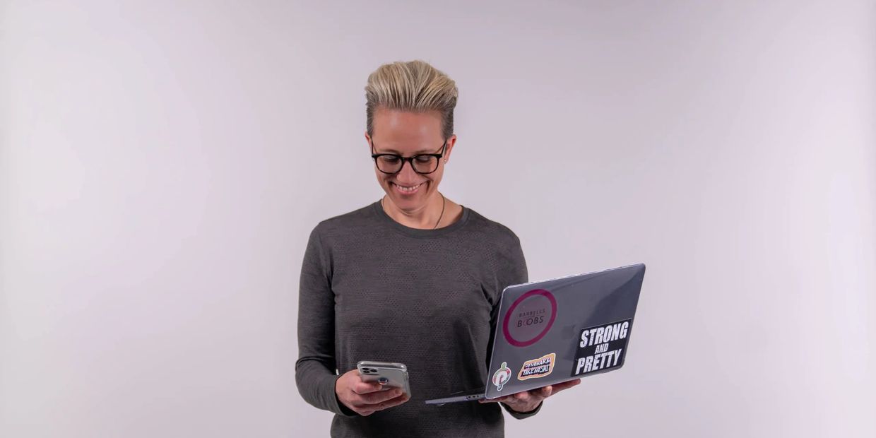 Chennelle Miller, Content Creator, Portfolio. Chennelle standing with computer, looking at phone