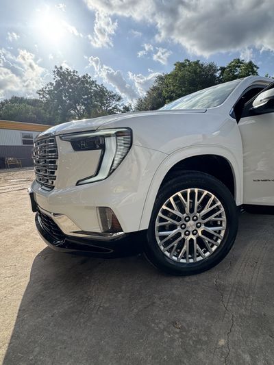 White SUV parked outdoors under a bright sky with clouds.
