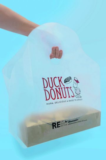 Hand holding a Duck Donuts bag with a box inside.