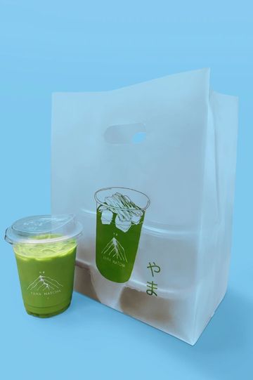 Green matcha drink with a carrying bag on blue background.