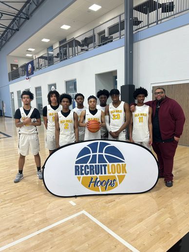 High school basketball team posing with coach behind Recruit Look Hoops sign.