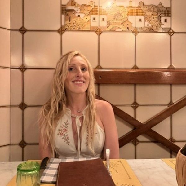 Woman sitting at a restaurant table smiling.