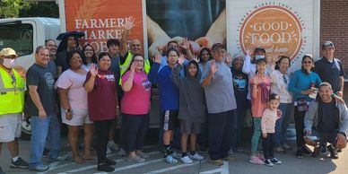 A diverse group of people posing happily at a farmers market.