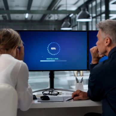 Two people anxiously watching a software installation progress on a computer screen.
