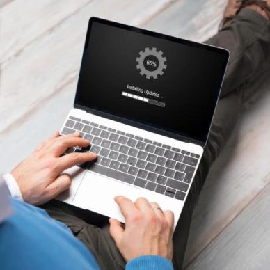 Person updating a laptop software with progress at 65%.