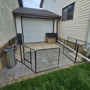 Small fenced patio area with a garage door and trash can.