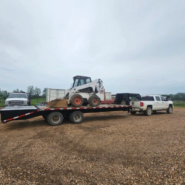 White truck towing a trailer with construction equipment.