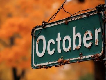 A street sign reading October with autumn leaves in the background.