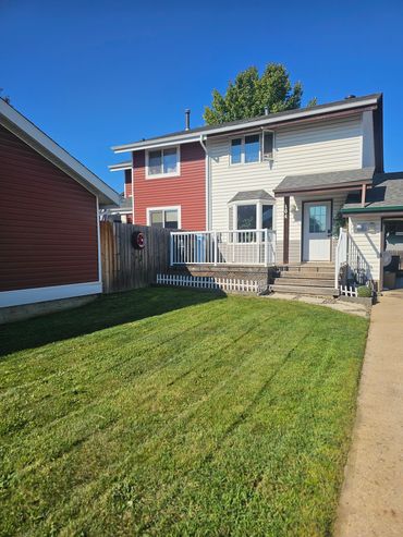 Two-tone house with a neatly mowed lawn under a clear sky.