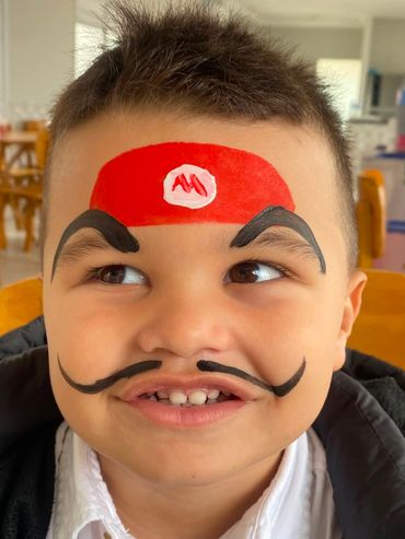 Boy with face paint resembling Mario from the video game series.