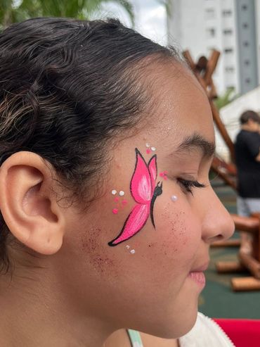 Young girl with a pink butterfly face painting on her cheek.
