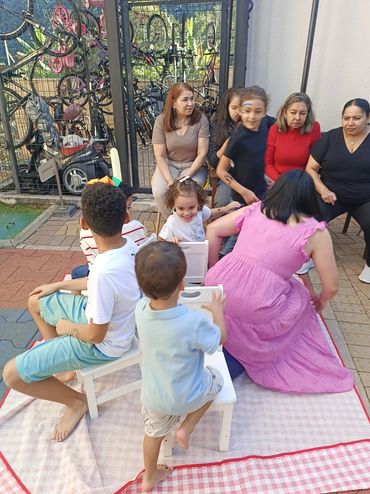 Children play musical chairs outdoors while adults watch.