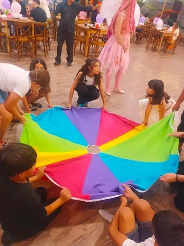 Children playing with a colorful parachute at a party.