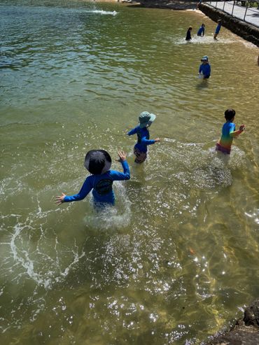 Children playing and splashing in shallow water under the sun.