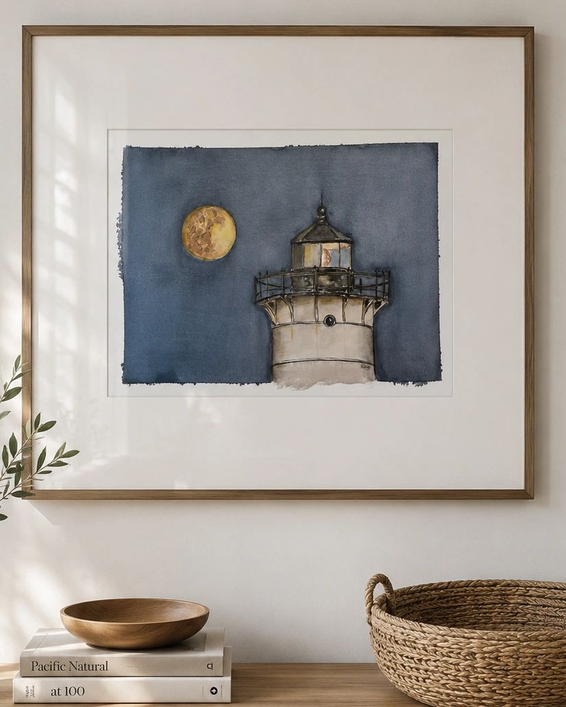 Framed lighthouse watercolor painting on wall above wooden dresser.