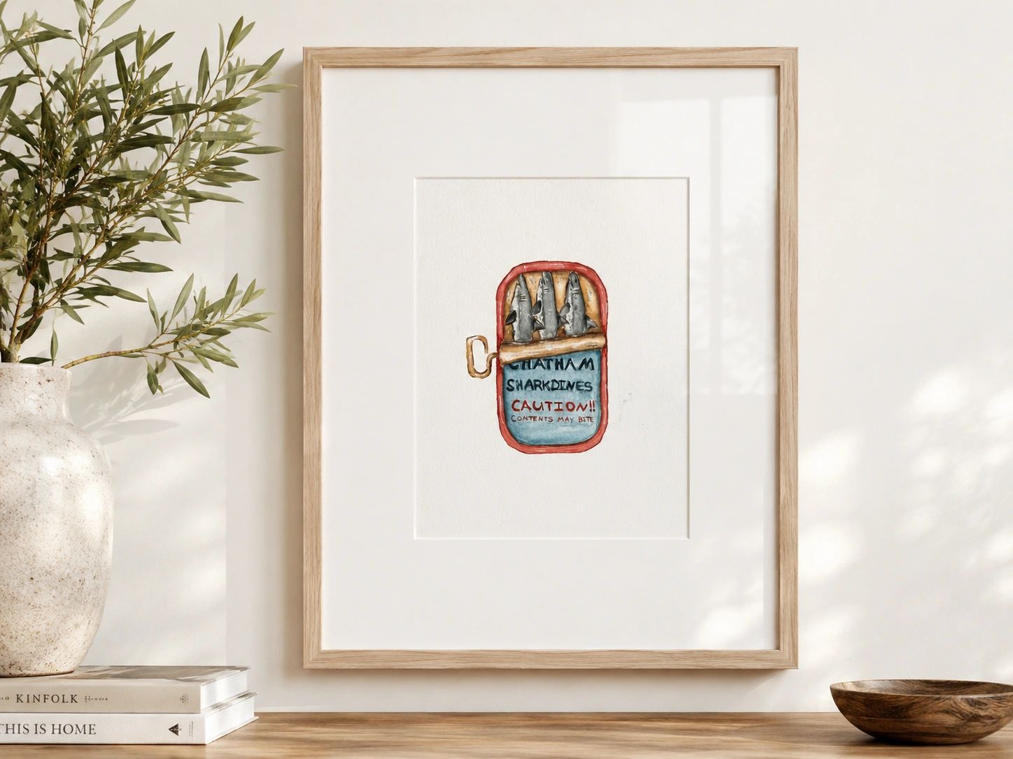 Framed art of a sardine can with sharks inside.