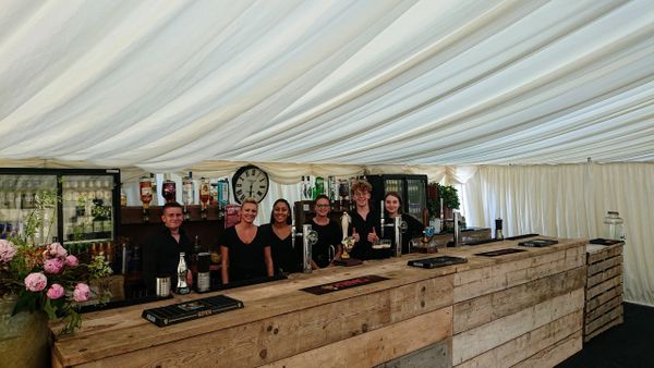 Staff at a village ball bar ready to serve alcohol on rustic bar 