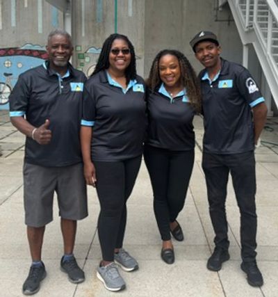Four people in matching black polo shirts posing together and smiling.