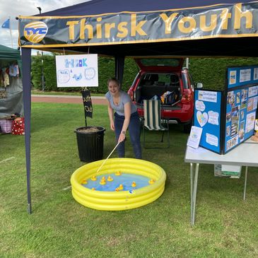 Young girl playing a duck fishing game at a Thirsk Youth tent.