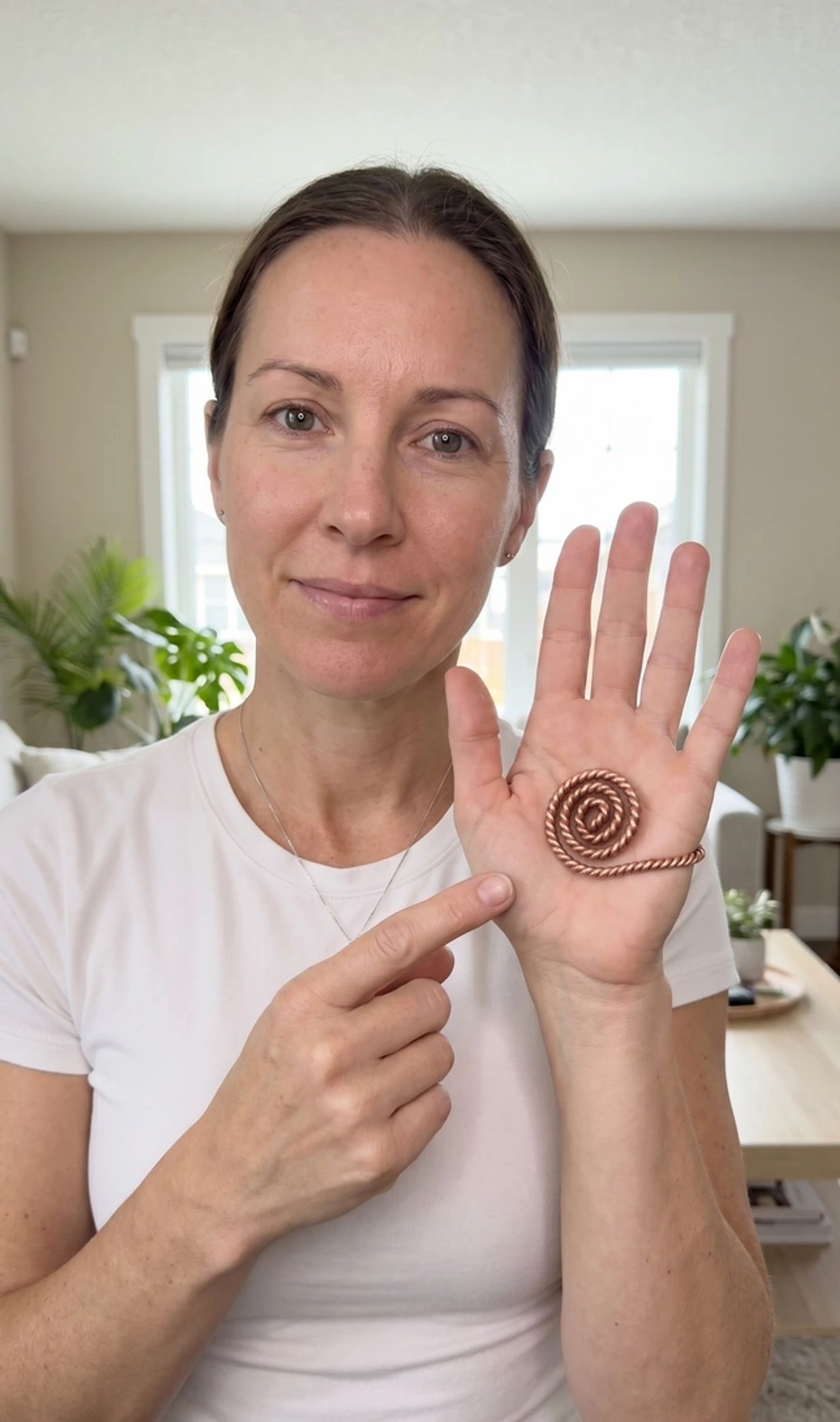 Woman pointing to spiral copper wire on her palm.