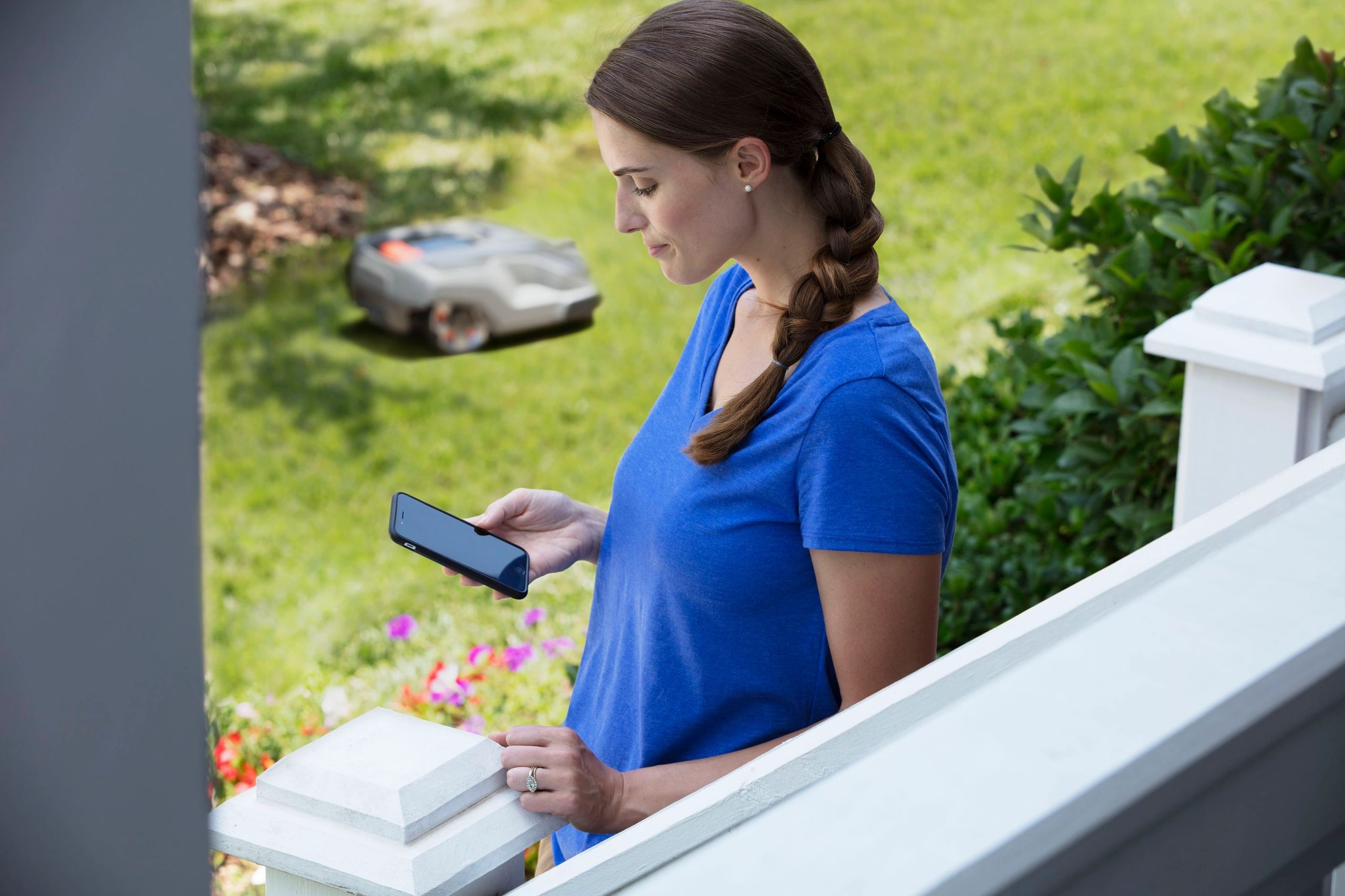 women holding phone controlling automower