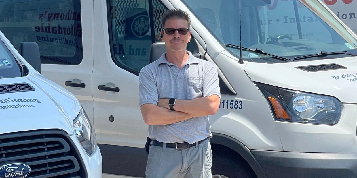 Owner of Affordable Heating and Air Conditioning in Murrieta, California, standing with his fleet of