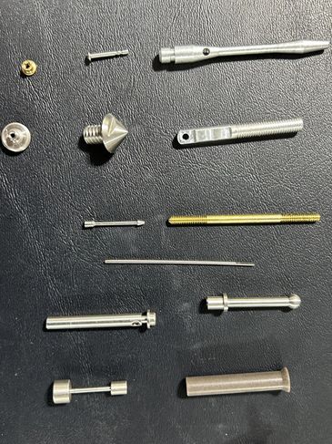 Various small metal mechanical parts arranged on a black surface.