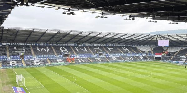 Empty Swansea City football stadium with green pitch.