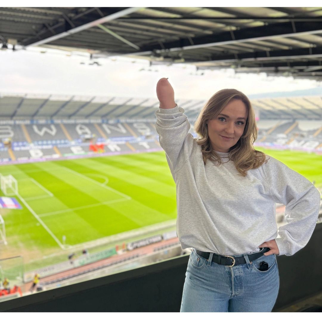 Woman posing confidently at football stadium.