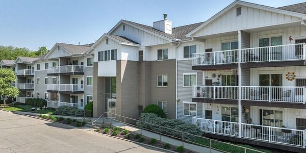 Modern three-story apartment complex with balconies and greenery.