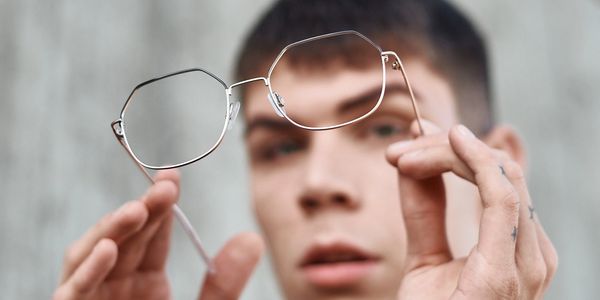 Darren is holding up his Designer Eyeglasses that he purchased at Vezina Opticians