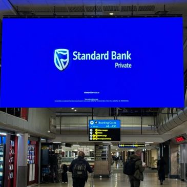 Large blue Standard Bank Private advertisement in an airport terminal.