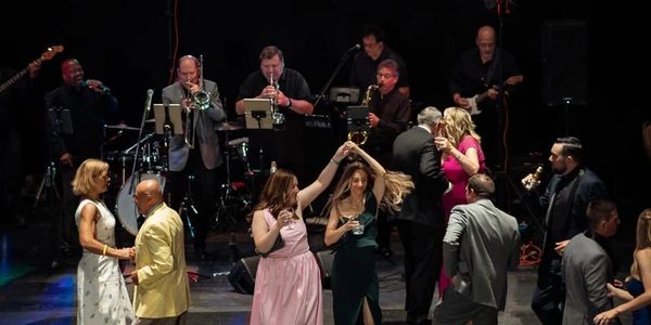 People dancing and live band performing on stage at a lively event.