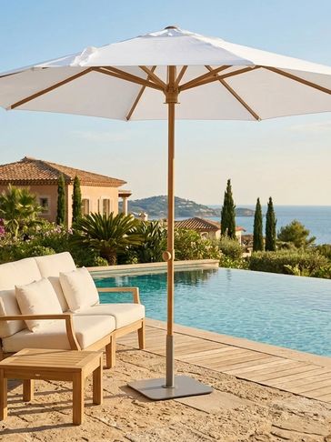 Outdoor seating with a white umbrella by a pool and scenic view.