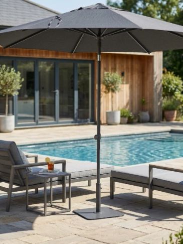 Modern poolside setup with gray umbrella and lounge chairs.