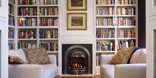 Bookshelves with books arranged vertically and horizontally.  Fireplace with sofas on both sides.