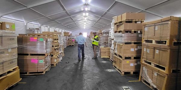 Image of a temporary tent structure with several pallets of supplies stored inside