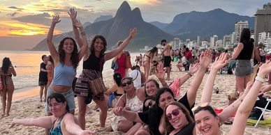 Grupo de personas felices en la playa al atardecer.