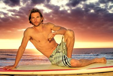 Shirtless man on a surfboard at sunset