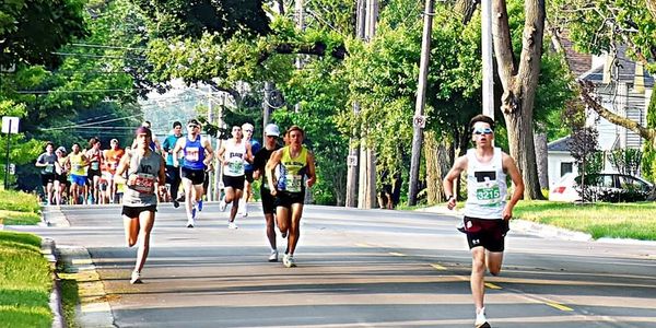 Runners competing in a road race on a tree-lined street.